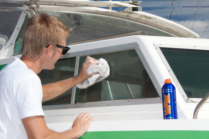 Man using VuPlex to clean a boat window with a cloth, showcasing effective plastic care and polish.